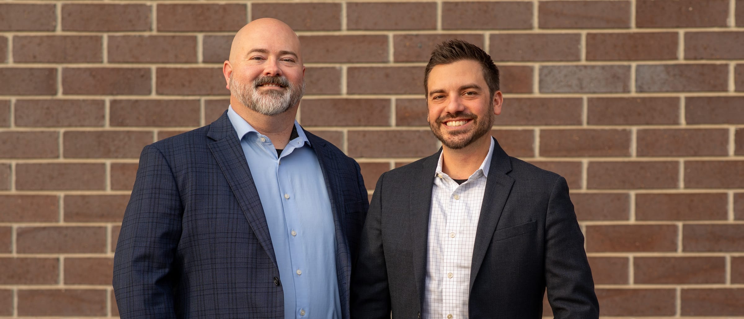 Adam Broadbent and Nicholas Barger, MadeLabs' founders, in blazers in front of a brick wall