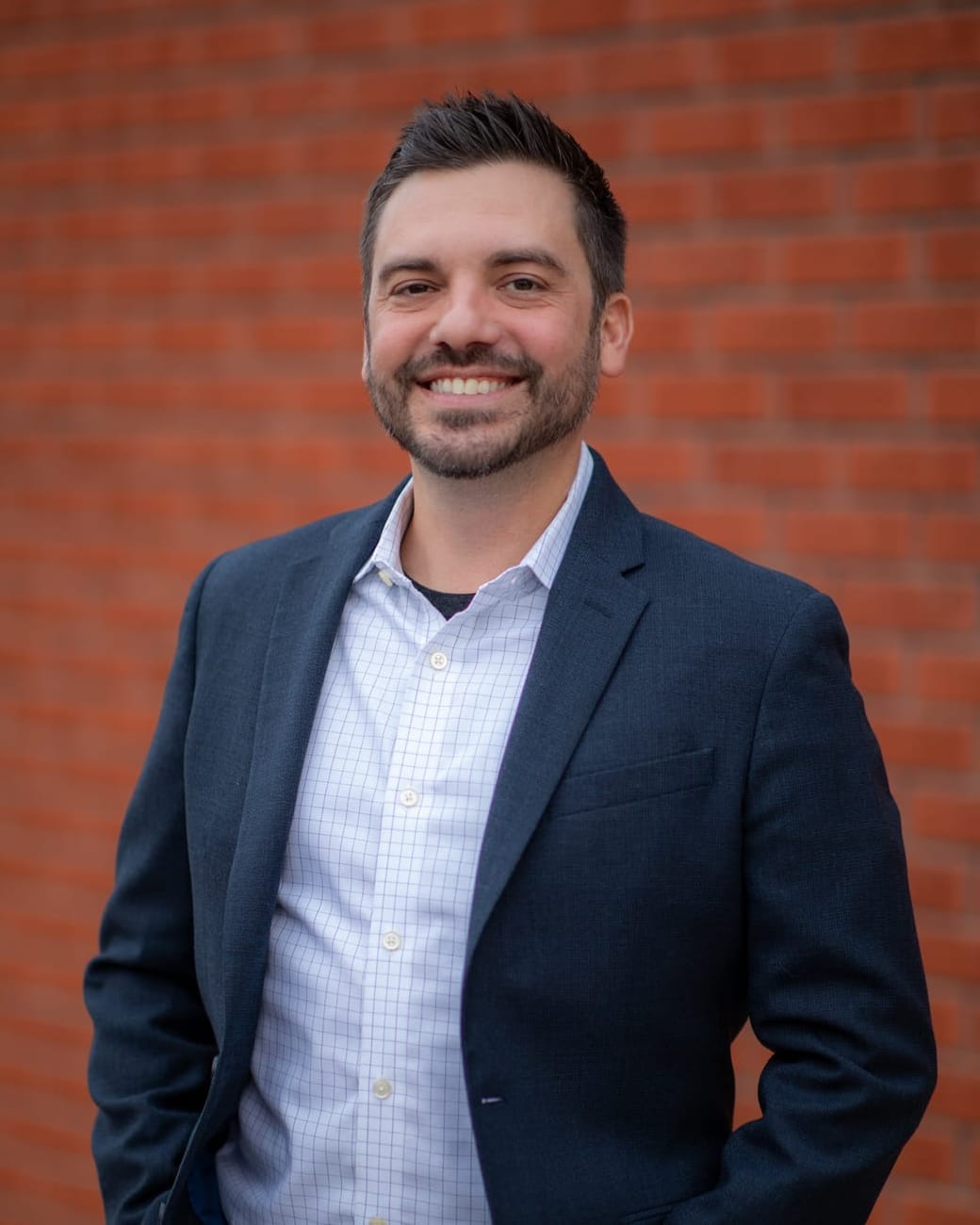 Nicholas Barger, CEO of MadeLabs, in a navy blazer in front of a red brick wall